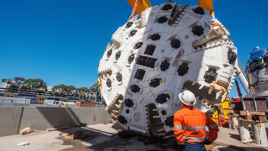 A woman standing in front of a large tunnel drilling machine