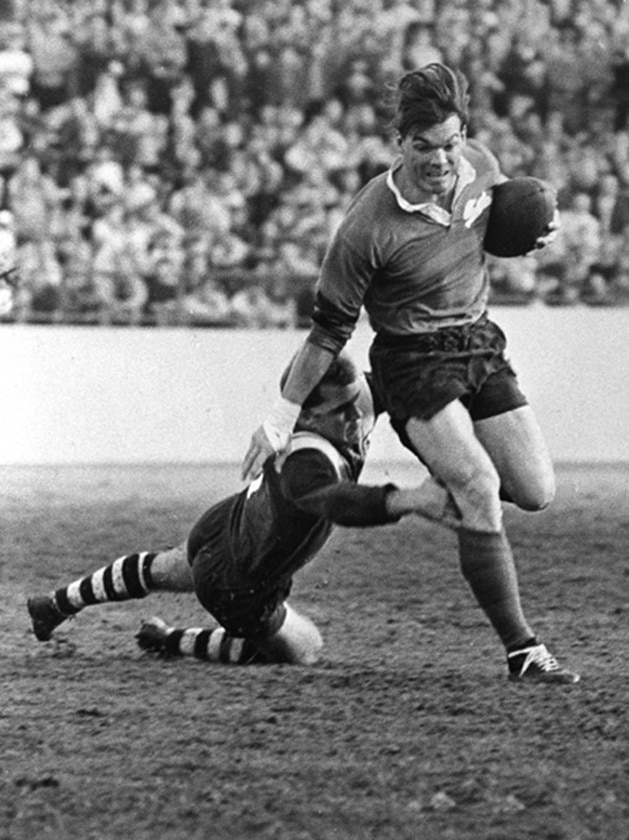 Brian James running past someone who is trying to tackle him during a rugby league game.