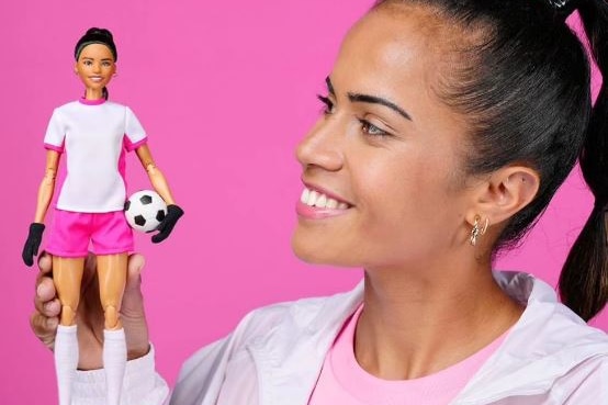 Mary Fowler holds up a Barbie doll in her likeness, wearing a soccer uniform, on her palm