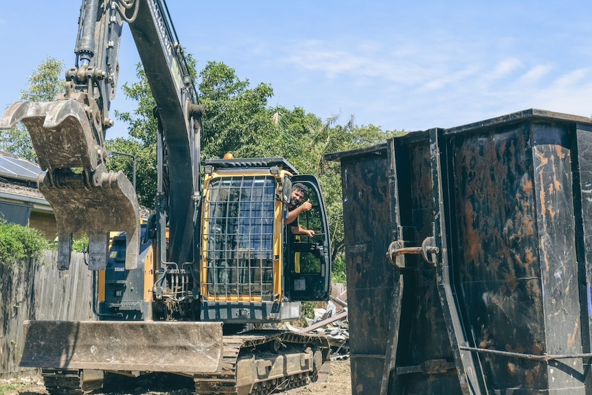 A man smiles as he sits in a bulldozer on a worksite