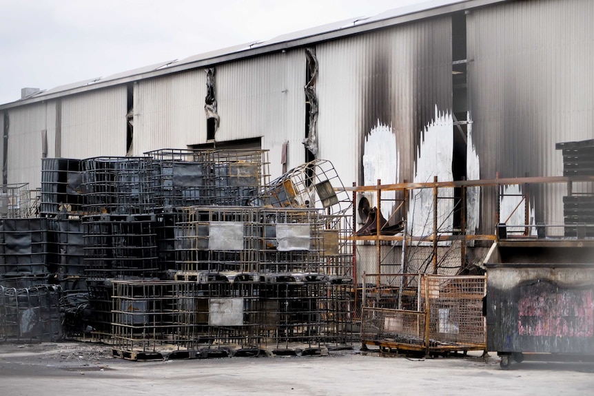 Burnt cages, melted plastic and sooty walls in a burned factory.