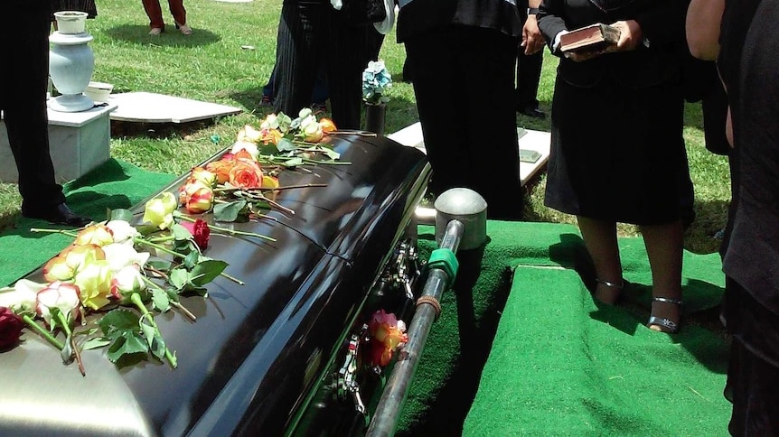 A coffin sits at a funeral.