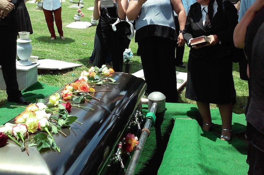 A coffin sits at a funeral.