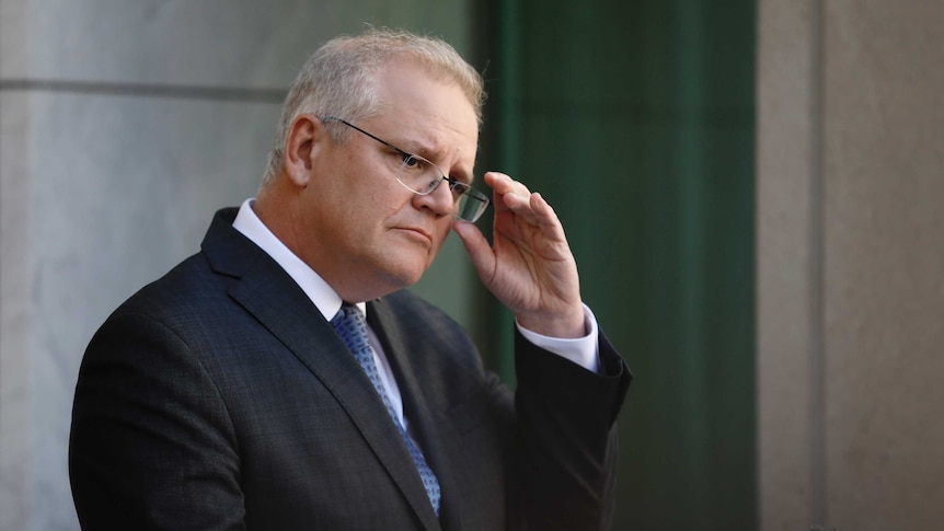 Morrison adjusts his glasses with his left hand.