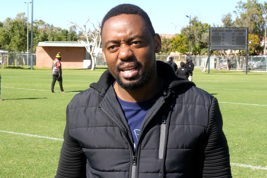 Devine Mezha speaks in a football field