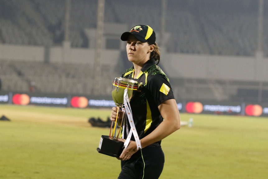 Australia's Tahlia McGrath holds a trophy after beating India in a Twenty20 series.