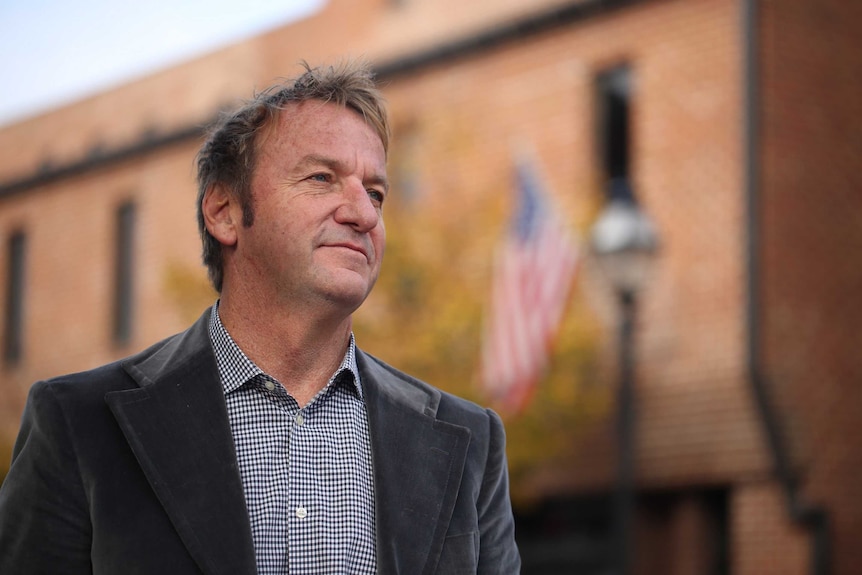 Close up  of Gavin Buckley, who has been elected mayor of Maryland's capital Annapolis, in the street with US flag in background