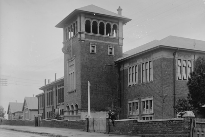 a black and white photo of an old school building with a bell tower.