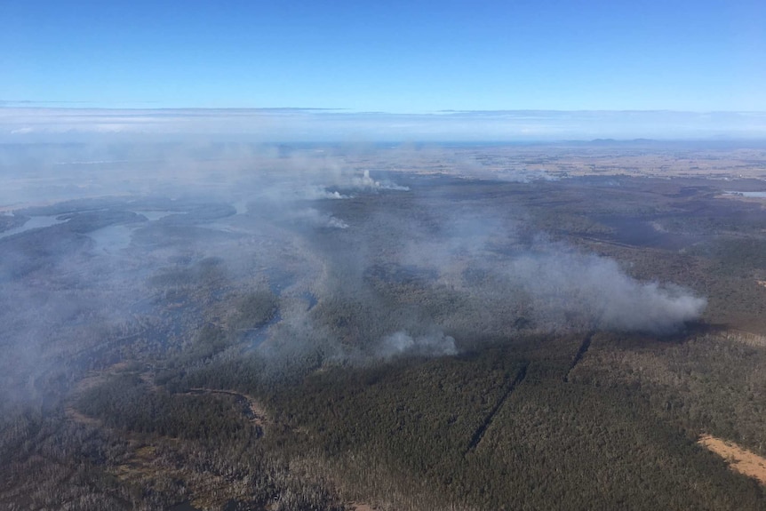 Aerial view of a bushfire burning across coastal wetland north-east of Kempsey, NSW.