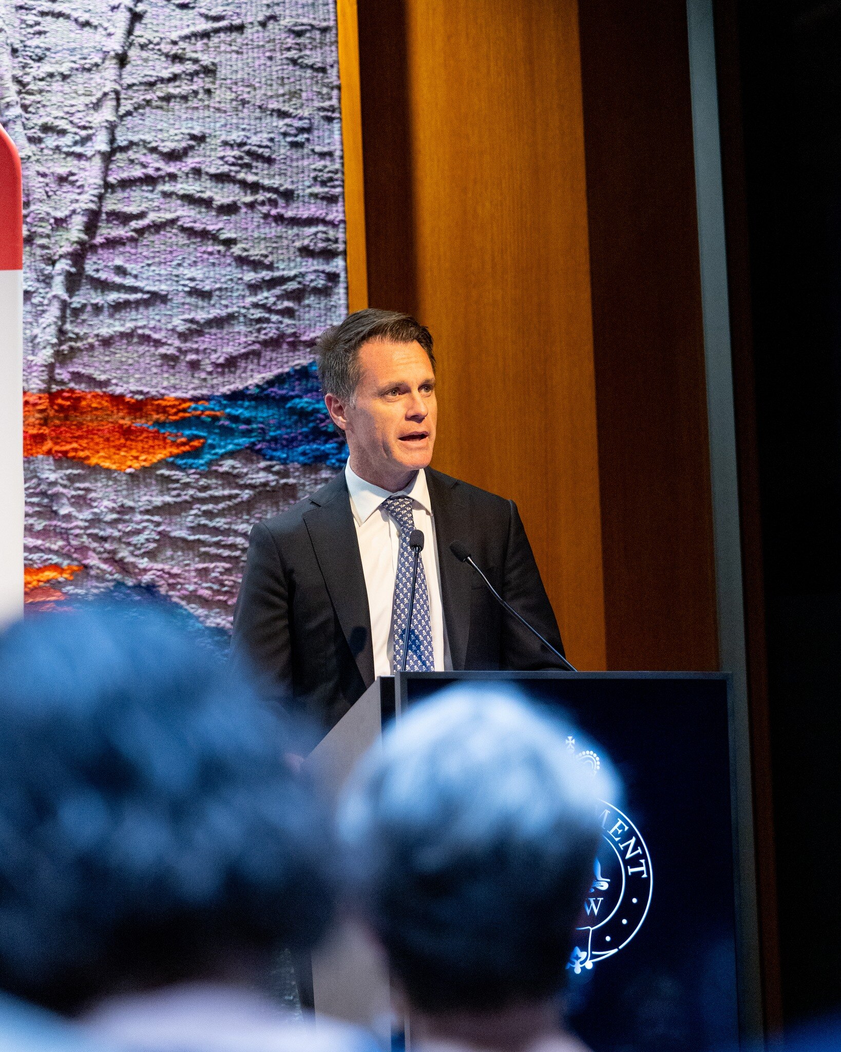 NSW Premier Chris Minns stands behins a lectern giving an address