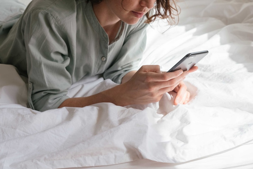 Woman looking at phone in bed