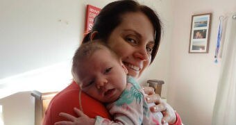 A woman holds her baby on her shoulder.