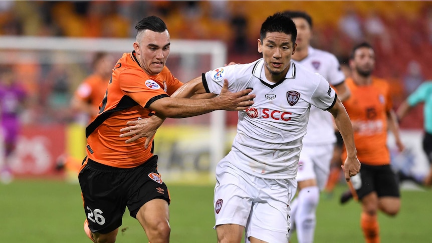 Roar player Nicholas D'Agostino (left) competes with Muangthong United player Aoyama Naoaki.