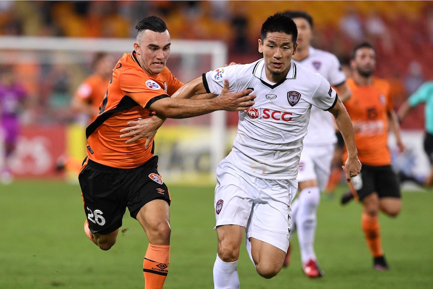 Roar player Nicholas D'Agostino (left) competes with Muangthong United player Aoyama Naoaki.