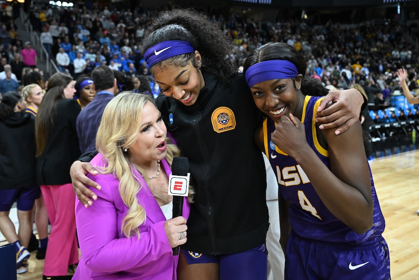 LSU basketball player Angel Reese puts her arms around an ESPN interviewer and teammate Flau'jae Johnson.