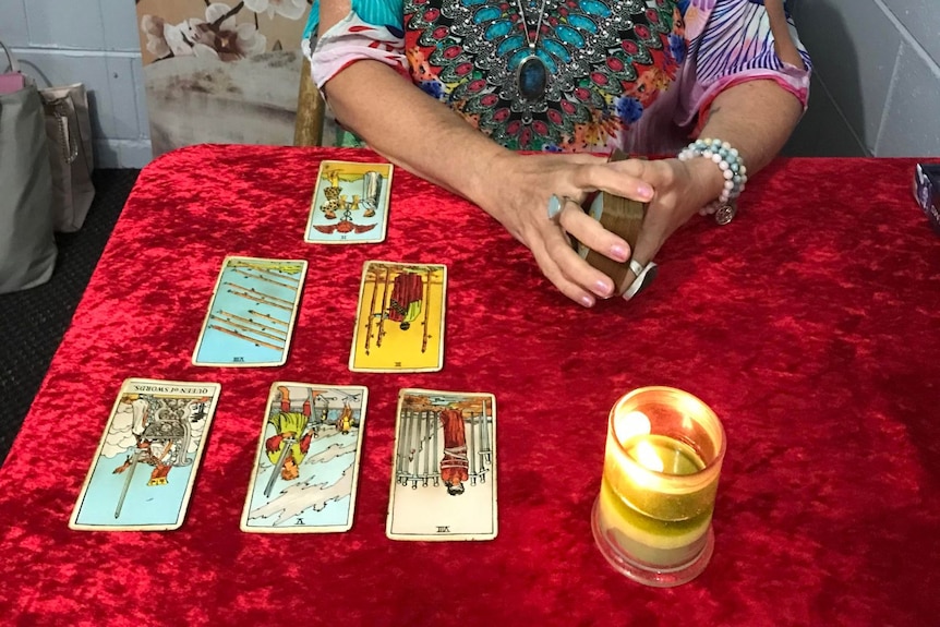 tarot cards laid out on table with candle light and hands shuffling deck. 