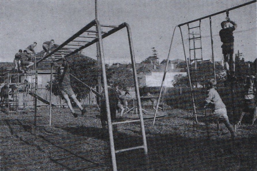 black and white archival photo of children playing on equipment in yard