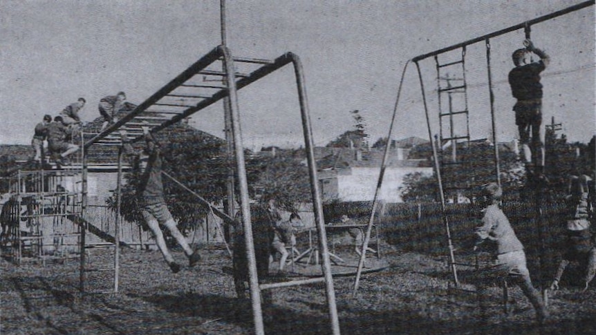 black and white archival photo of children playing on equipment in yard