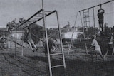 black and white archival photo of children playing on equipment in yard