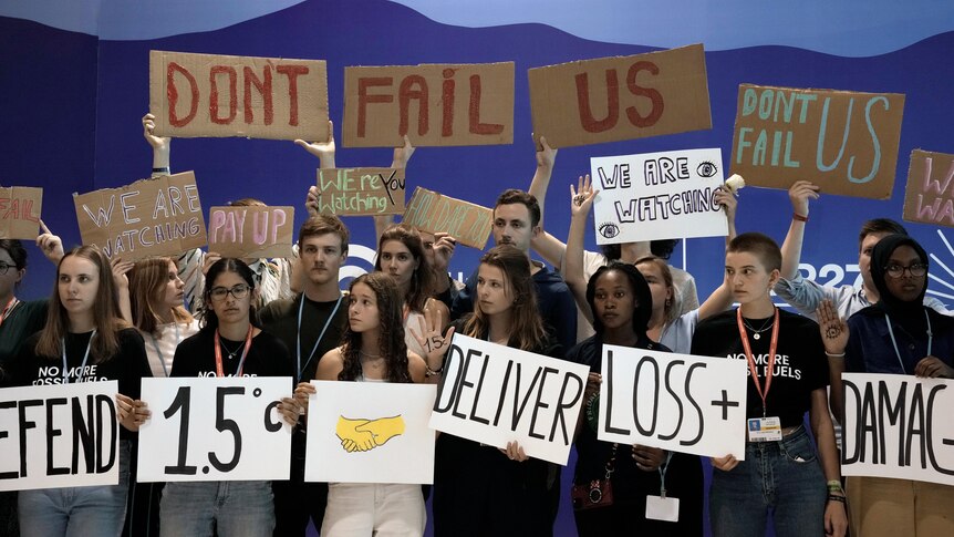 A group of young people hold signs including 'don't fail us'. 