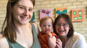 Woman holding a baby and Hales leaning in, all smiling at camera.