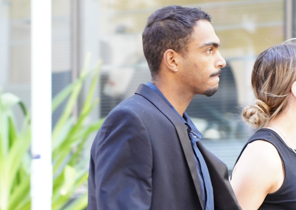 Roosevelt Williams Jr wears a suit as he walks along a street. 