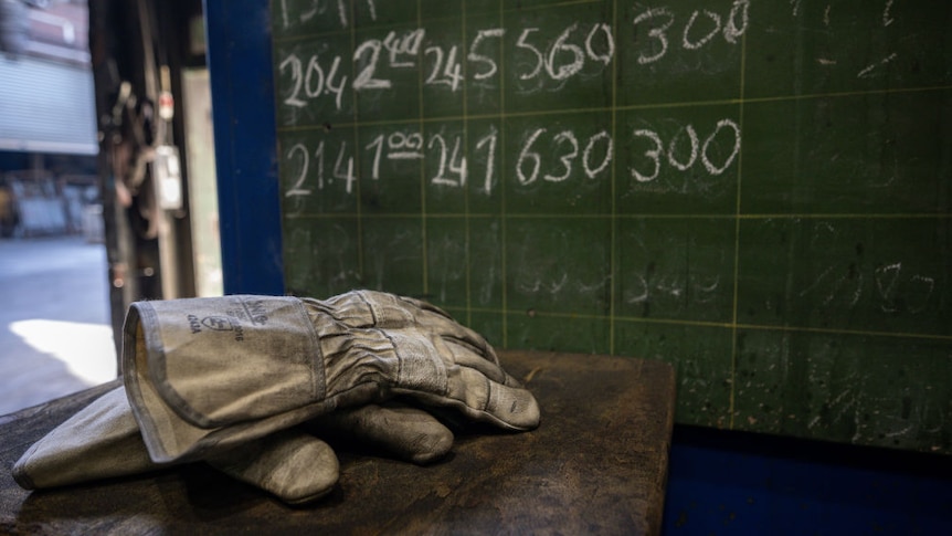 workers gloves in front of a chalkboard at a foundry in Germnay.