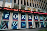 Large letters spelling FOX NEWS fill windows of an office building, while an electronic message reads "President Trump..."