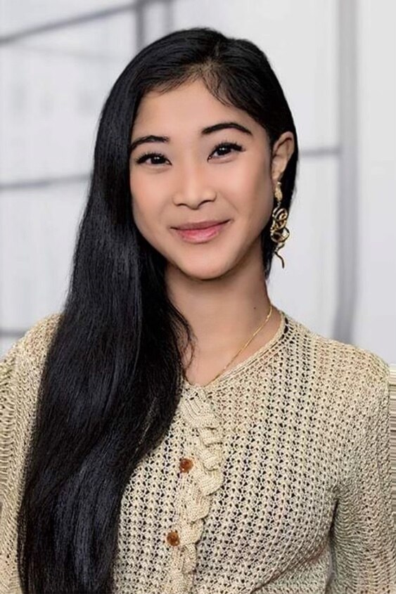 A woman smiling. She has long, black hair and a knitted beige shirt.