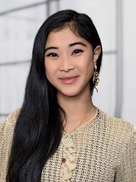 A woman smiling. She has long, black hair and a knitted beige shirt.