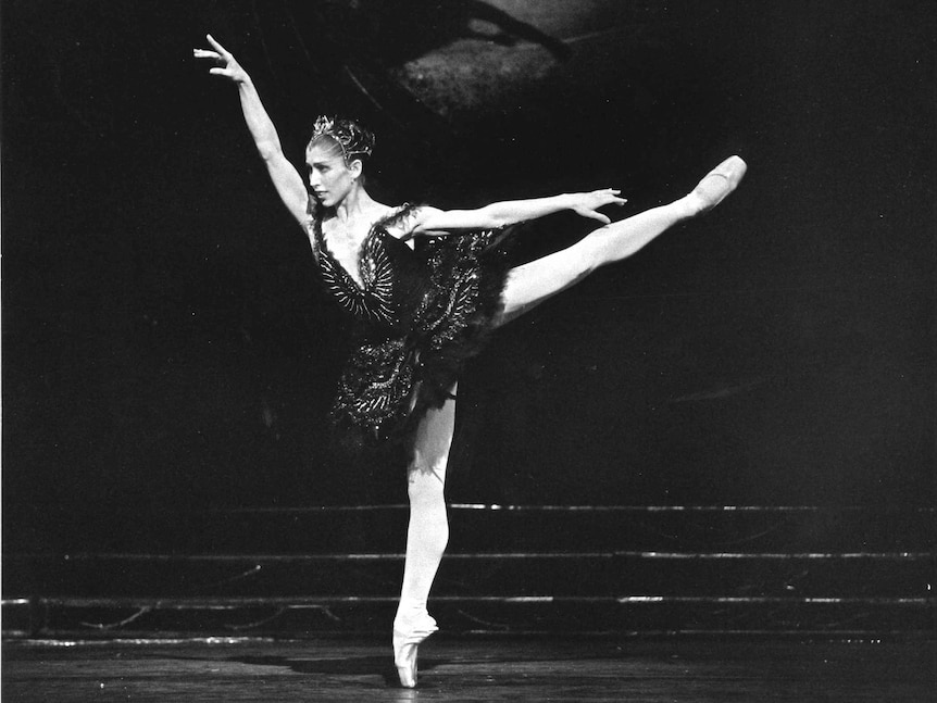 A female ballet dancer poses on stage