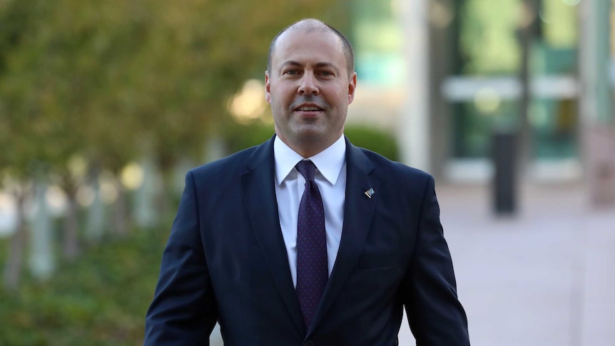 Treasurer Josh Frydenberg walks towards the media at Parliament House on Budget day.