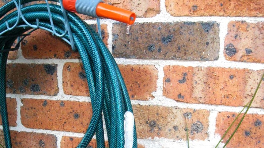 An ice spike forms on a garden hose at a house on a freezing morning.