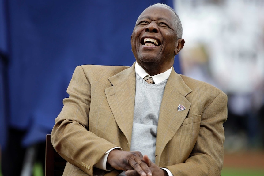 Hank Aaron laughs while sitting down at a ceremony celebrating the 40th anniversary of his 715th career home run in 2014.