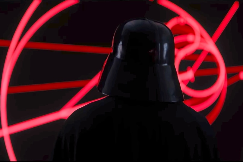 The back of Darth Vader as he looks a red glowing map.