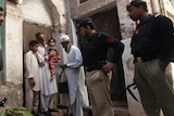 Police stand guard as a health worker visits homes during a polio vaccination campaign in Peshawar