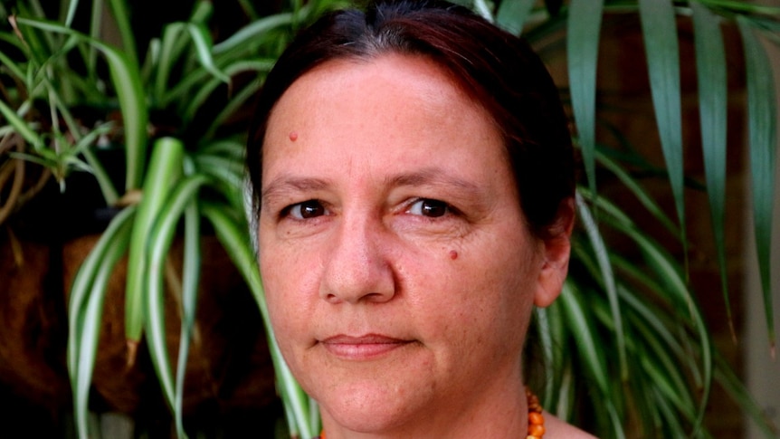 A close-up photo of a woman standing in front of some pot plants.