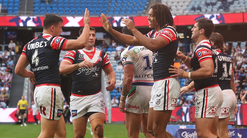 Sydney Roosters players congratulate Dominic Young on a try against the Warriors in an NRL game.