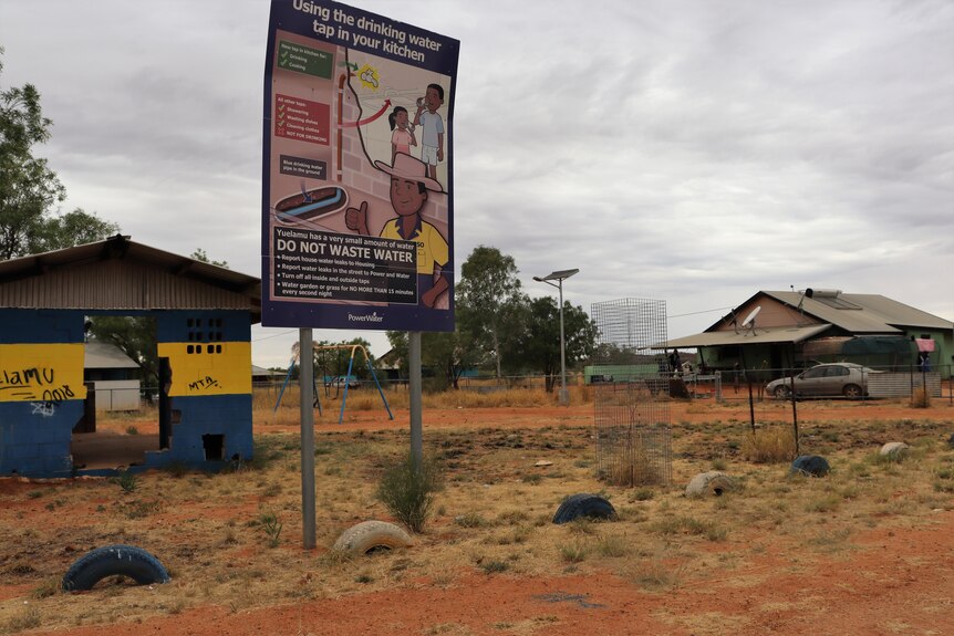 large sign that says 'do not waste water' with cartoon drawing in remote Aboriginal community