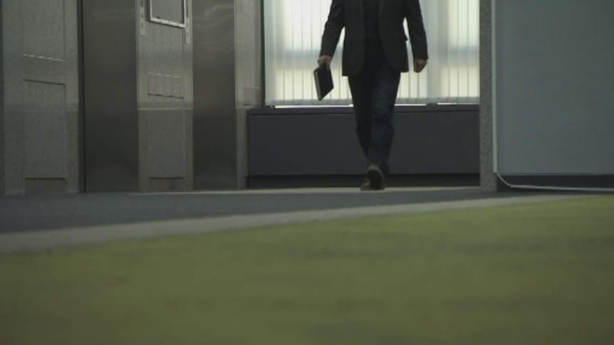 Person in a suit holding a book.