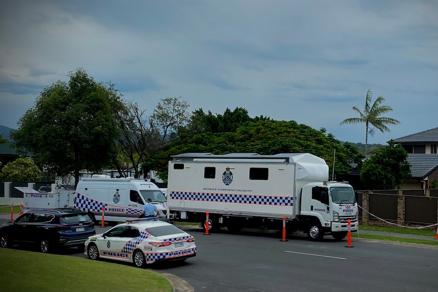multiple police vehicles including a mobile forensics lab parked on a suburban street