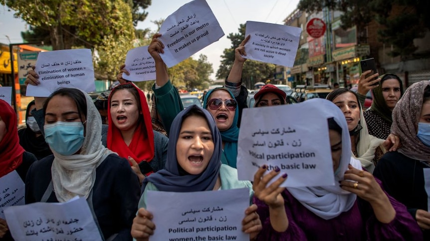 afghan women holding signs protesting their freedom wearing coloured hijabs