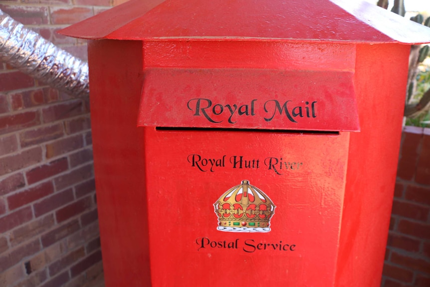 A red post box with a crown logo on it and the words Royal Mail, Royal Hutt River Postal Service.