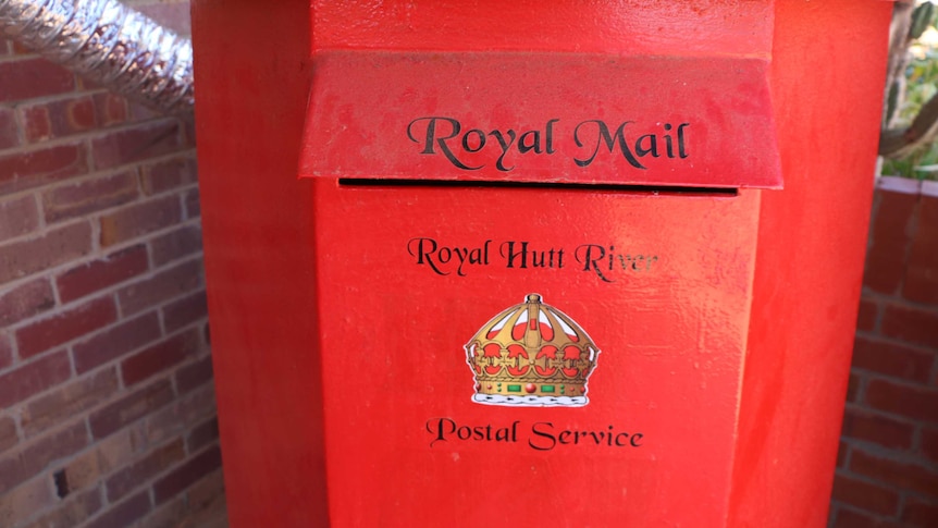 A red post box with a crown logo on it and the words Royal Mail, Royal Hutt River Postal Service.