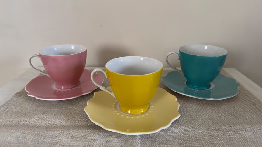 A set of tea cups and saucers of different colours.