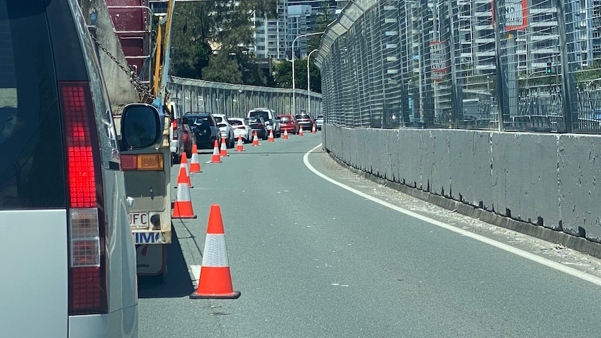 Vehicles queued up along a road that is being converted into race-track street circuit. 