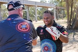 Aboriginal boxing coach Malachi Johnson practices his technique with Bundaberg Senior Constable Mick Gray at a park in Bundaberg