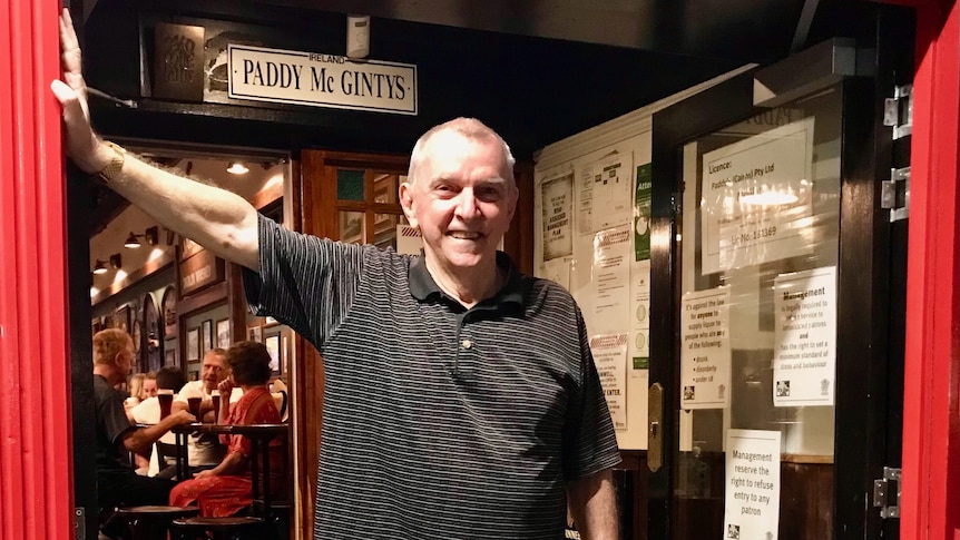 A man smiles at the camera as he stands in the doorway of his Irish pub.