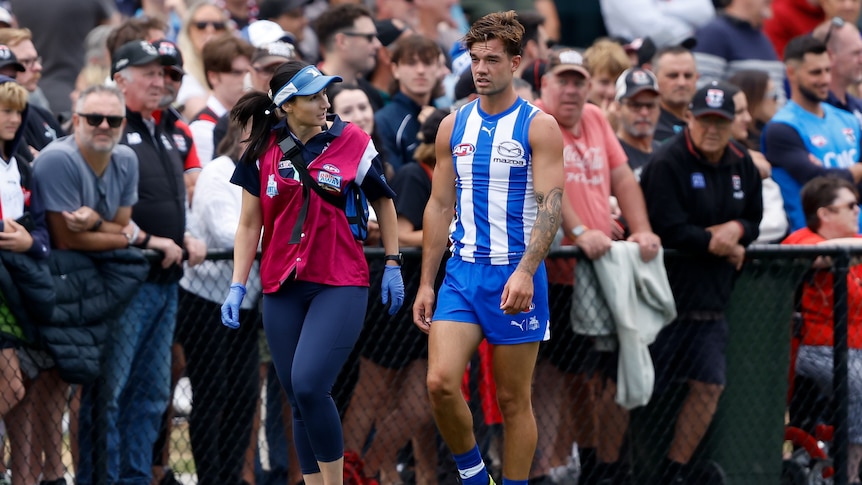 North Melbourne Kangaroos' Jy Simpkin walks off the field with a training during an AFL preseason game.