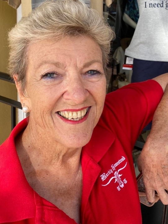 A close-up of the face of a woman wearing a red T-shirt and smiling widely. 